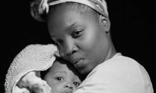 Femme pensive serrant son bébé contre elle. Photographe : Andrae Ricketts.