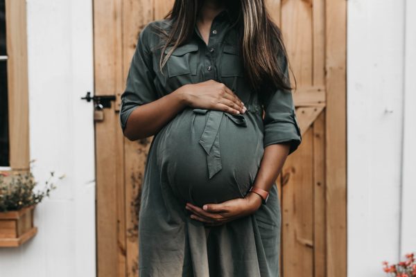 Femme enceinte avec les mains autour du ventre. Photographe : Camylla Battani